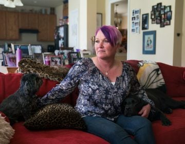 Michel, joined on the couch by longtime pet Blade and service dog Lizzy, says at least three male service members assaulted or molested her between 1990 and 2005. (Claire Harbage/NPR)