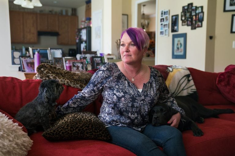 Michel, joined on the couch by longtime pet Blade and service dog Lizzy, says at least three male service members assaulted or molested her between 1990 and 2005. (Claire Harbage/NPR)