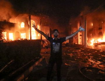 An Iraqi protester stands flashing the victory gesture outside the burning headquarters of the Iranian Consulate in Basra on Sept. 7.