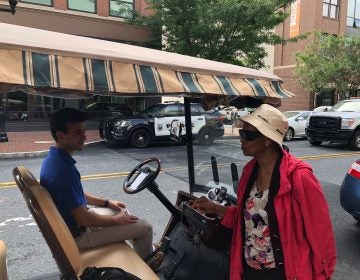 Eunice LaFate quizzes Andrew Cercena about the new golf cart taxi service he's starting for  Buccini/Pollin Group. (Cris Barrish/WHYY)