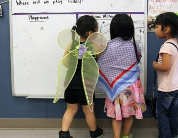 Students play dress-up and draw on a whiteboard in a Christopher House preschool class. (Jackie Mader/The Hechinger Report)