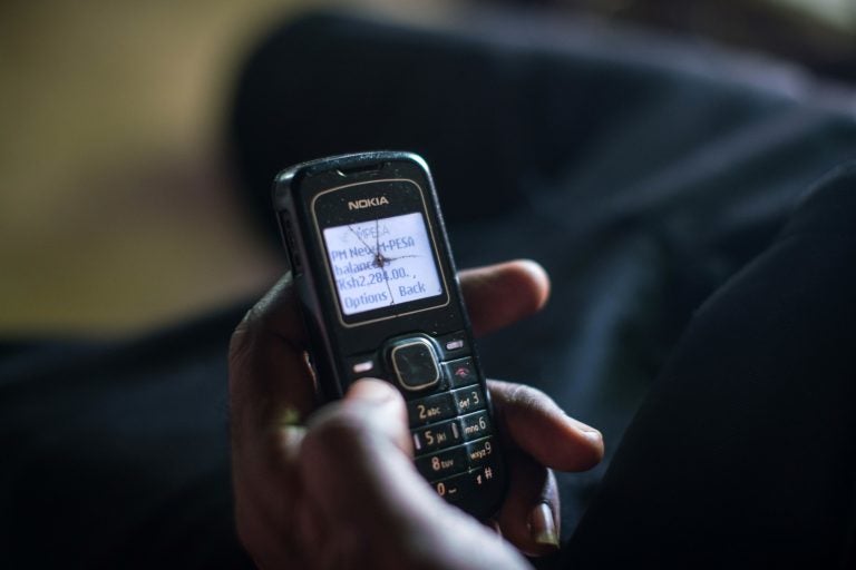 A man checks his phone to confirm that the charity GiveDirectly has transferred a cash grant to his account. (Nichole Sobecki for NPR)