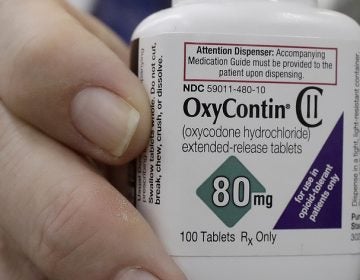 In this April 2, 2018 photo, pharmacist Steve Protzel poses for photos holding a bottle of OxyContin at Daniel's Pharmacy in San Francisco. (AP Photo/Jeff Chiu)