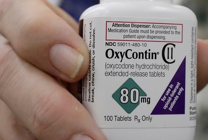 In this April 2, 2018 photo, pharmacist Steve Protzel poses for photos holding a bottle of OxyContin at Daniel's Pharmacy in San Francisco. (AP Photo/Jeff Chiu)