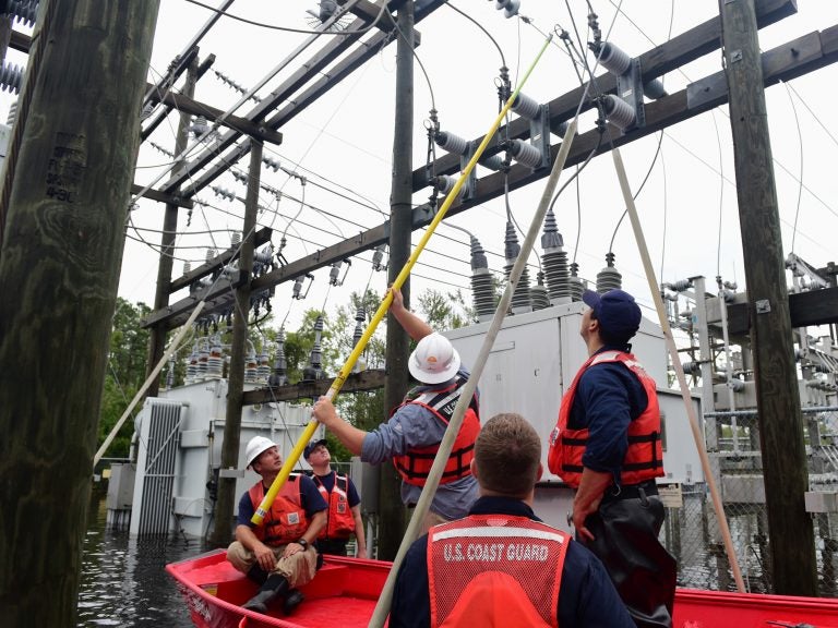 Members of the Coast Guard Shallow-Water Response team escort utility workers to a flooded substation to inspect transformers in Newport, N.C., on Sunday.