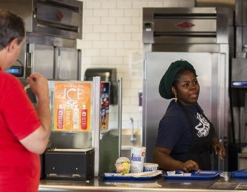 Hawa Hamadi serves up an order at Ivar's Fish Bar, the to-go section of Ivar's on the waterfront pier, on Wednesday, August 15, 2018 in Seattle, Washington. Ivar's is one of the local businesses affected by Seattle's Secure Scheduling Ordinance, which took effect in July 2017, aiming to establish more predictable work schedules for employees of large retail and food establishments. (Lindsey Wasson for the Inquirer)