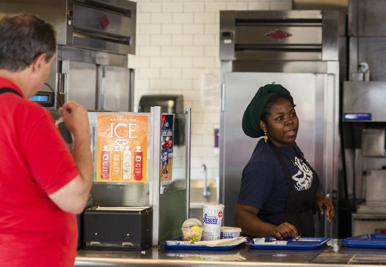 Hawa Hamadi serves up an order at Ivar's Fish Bar, the to-go section of Ivar's on the waterfront pier, on Wednesday, August 15, 2018 in Seattle, Washington. Ivar's is one of the local businesses affected by Seattle's Secure Scheduling Ordinance, which took effect in July 2017, aiming to establish more predictable work schedules for employees of large retail and food establishments. (Lindsey Wasson for the Inquirer)