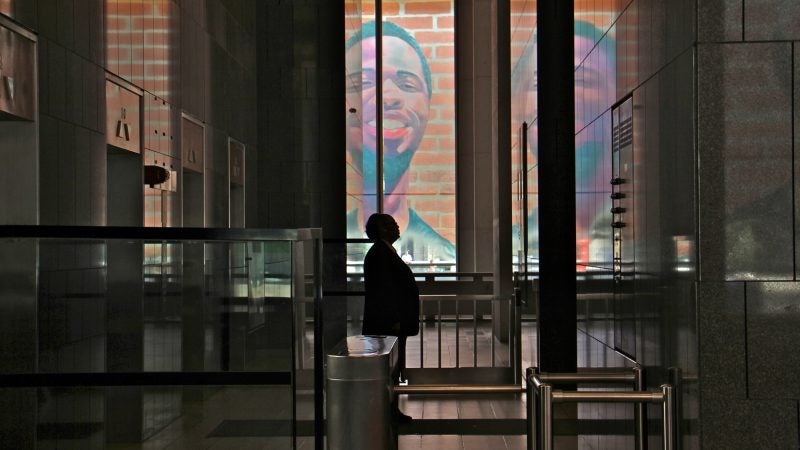 The first floor of the Municipal Services Building is wrapped with the portraits of 17 formerly incarcerated young men and women as part of the Mural Arts 