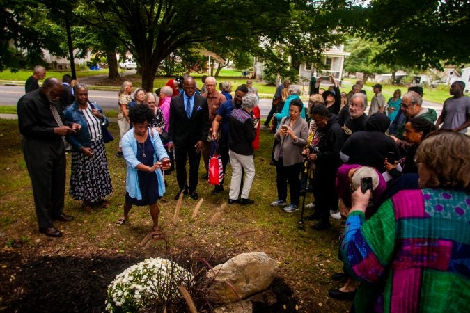 Attendees gather around a memorial stone during a service for the forgotten slaves buried on the grounds of Middletown Friends Meeting at Langhorne, Pa. on Saturday, Oct. 6, 2018. (Brad Larrison for WHYY)