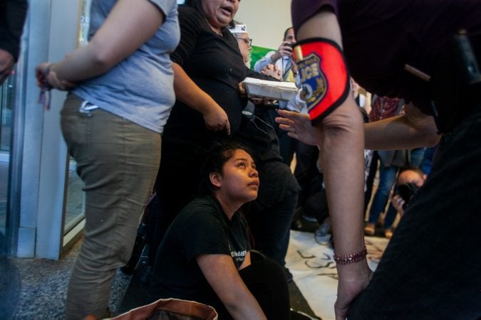 Under threat of arrest Keyri Artillero Apolonio, 14, and her mother Carmela Apolonio Herandez continued to stand in front of an entrance at 2000 Market Street after demanding a meeting with U.S. Sen.  Bob Casey Wednesday. (Brad Larrison for WHYY)