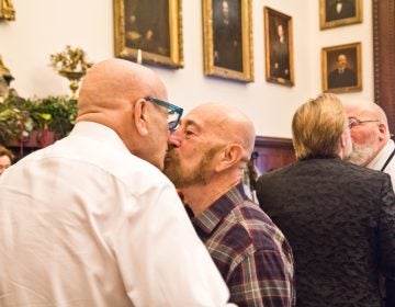 Charles Massucci kisses his partner of 47 years, Joseph DiDio, as they renew their vows at the National Coming Out Day event at City Hall Thursday. (Kimberly Paynter/WHYY)