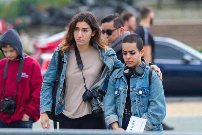 Angela Gervasi (left) consoles Celeste Rivera while listening to speakers at an event to commemorate the people who died in Hurricane Maria in Puerto Rico. (Miguel Martinez for WHYY)