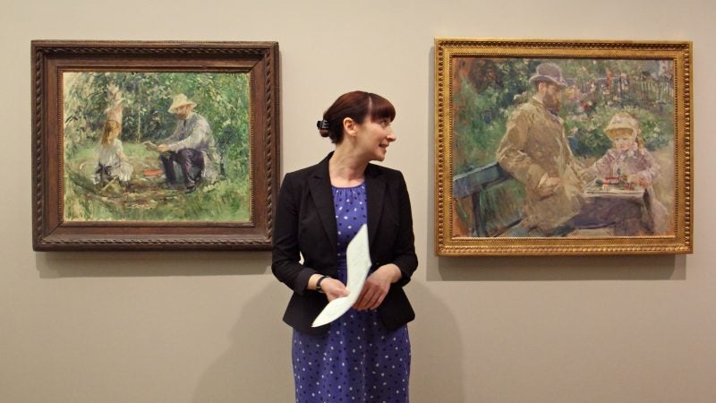 Curator Nicole Myers of the Dallas Museum of Art stands between two Berthe Morisot paintings depicting the artist's husband, Eugène Manet, and daughter, Julie. Eugène Manet is the only man depicted in the Barnes Foundation exhibit of Morisot's work. (Emma Lee/WHYY)