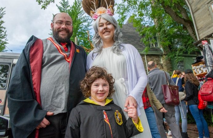 In Harry Potter regalia, John Bangor, Ellie Bangor, 6, and Lee Bangor from Doylestown, take in the sites on Germantown Avenue. (Jonathan Wilson for WHYY)