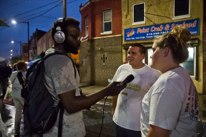 Reporter Darryl Murphy talks to Point Breeze residents Kelly Murray and Anthony Coskuy at the Point Breeze Night Market. (Kimberly Paynter/WHYY)