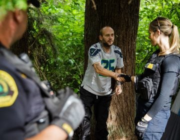 Social worker, Lauren Rainbow (right), along with Police Officer Mike Buell (left) meet a man illegally camped in the woods in Snohomish County. They are part of a new program in the county that helps people with addiction, instead of arresting them. (Leah Nash for Finding Fixes Podcast)