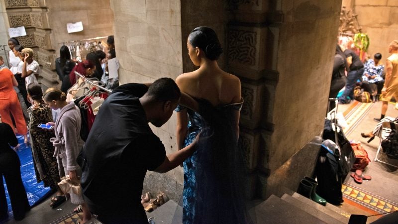 Designer Reginald Lee makes adjustments to one of his evening wear designs at Philadelphia Fashion Week, held at Dilworth Park. (Kriston Jae Bethel for WHYY)