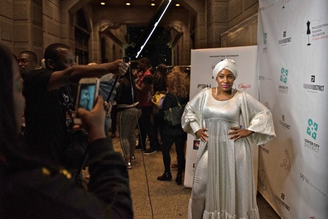 A Philadelphia Fashion Week attendee posses for her own photoshoot following Friday night's runway show, held at Dilworth Park. (Kriston Jae Bethel for WHYY)