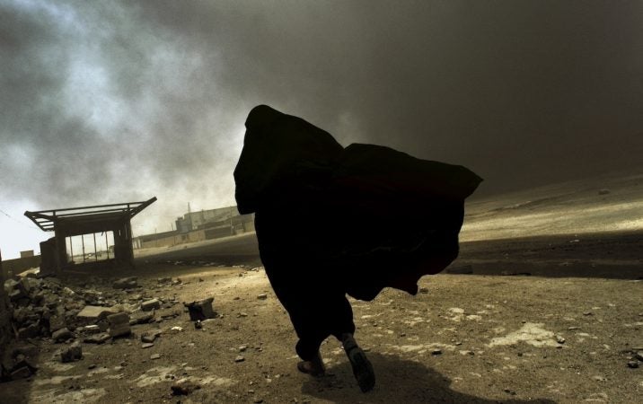 An Iraqi woman walks through a plume of smoke rising from a massive fire at a liquid
gas factory as she searches for her husband in Basra, Iraq, May 2003.
