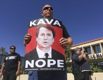 A man holds up a sign during a protest against Supreme Court nominee Brett Kavanaugh outside the offices of Arizona Sen. Jeff Flake in Phoenix, Friday, Sept. 28, 2018. (AP Photo/Patricio Espinoza)