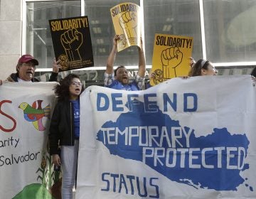 In this Monday, March 12, 2018, file photo, supporters of temporary protected status immigrants hold signs and cheer at a rally outside of a federal courthouse in San Francisco. A judge on Wednesday, Oct. 3, 2018, blocked the Trump administration from ending protections. (Jeff Chiu/AP Photo, File)