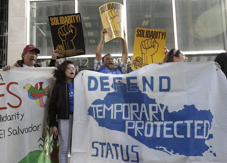 In this Monday, March 12, 2018, file photo, supporters of temporary protected status immigrants hold signs and cheer at a rally outside of a federal courthouse in San Francisco. A judge on Wednesday, Oct. 3, 2018, blocked the Trump administration from ending protections. (Jeff Chiu/AP Photo, File)