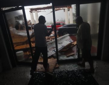 Hotel employees look at a canopy that just collapsed, as Hurricane Michael passes through in Panama City Beach, Fla., Wednesday, Oct. 10, 2018. (AP Photo/Gerald Herbert)