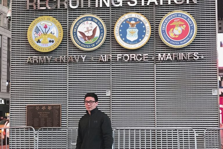 This November 2017 photo provided by Badamsereejid Gansukh shows him in front of a U.S. military recruiting office in New York's Times Square. Gansukh, whose recruiter told him his Turkish language skills would be an asset to the military, said he didn’t know he was discharged at all until he asked his congressman’s office in the summer of 2018 to help him figure out why his security screening was taking so long. (Courtesy of Badamsereejid Gansukh via AP)