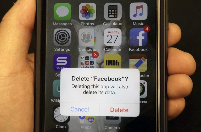 In this March 27, 2018, file photo, a reporter holds a phone showing the Facebook app in San Francisco. It might not seem like a big deal to have  long-forgotten accounts on social media linger. But with hacking in the news constantly, including a breach affecting 50 million Facebook accounts, you might not want all that data sitting around. (Jeff Chiu/AP Photo, File)