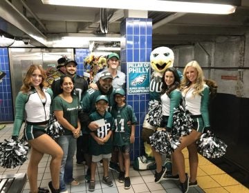 In this October 2018 photo provided by Matt Liston, Philadelphia Eagles fan Jigar Desai poses with his family, friends and members of the Philadelphia Eagles Cheerleaders in front of the subway pillar he ran into earlier this year at Ellsworth Station on the Broad Street subway line in Philadelphia. The moment in the spotlight isn’t over yet for Desai who stumbled into fame as a viral video star after running into the subway pillar. Desai is now the subject of an NFL digital short feature, shot ahead of the Oct. 28 Eagles game against the Jacksonville Jaguars in London.  (Matt Liston via AP)