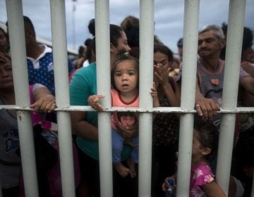 Migrants bound for the U.S.-Mexico border wait on a bridge that stretches over the Suchiate River, connecting Guatemala and Mexico, in Tecun Uman, Guatemala, Friday, Oct. 19, 2018.  The gated entry into Mexico via the bridge has been closed.  The U.S. president has made it clear to Mexico that he is monitoring its response. On Thursday he threatened to close the U.S. border if Mexico didn't stop the caravan. (AP Photo/Oliver de Ros)
