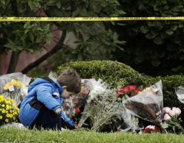 Gideon Murphy places a flower at the Tree of Life Synagogue in Pittsburgh, Sunday, Oct. 28, 2018. Robert Bowers, the suspect in Saturday's mass shooting at the synagogue, expressed hatred of Jews during the rampage and told officers afterward that Jews were committing genocide and he wanted them all to die, according to charging documents made public Sunday. (AP Photo/Matt Rourke)
