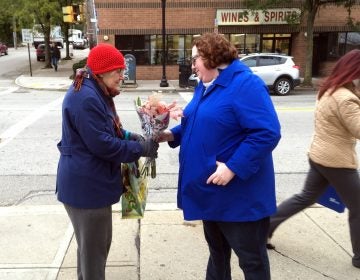 Kristin Wessell, right, hands a bouquet of flowers to Marianne Novy on Murray Avenue in the Squirrel Hill neighborhood of Pittsburgh, Monday, Oct. 29, 2018. Wessell was volunteering to bring some cheer to the neighborhood following Saturday's deadly attack on the nearby Tree of Life synagogue. Neither woman thinks President Trump should come to town. (AP Photo/Allen G. Breed)