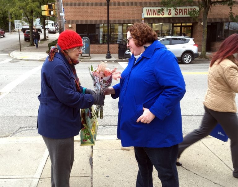 Kristin Wessell, right, hands a bouquet of flowers to Marianne Novy on Murray Avenue in the Squirrel Hill neighborhood of Pittsburgh, Monday, Oct. 29, 2018. Wessell was volunteering to bring some cheer to the neighborhood following Saturday's deadly attack on the nearby Tree of Life synagogue. Neither woman thinks President Trump should come to town. (AP Photo/Allen G. Breed)