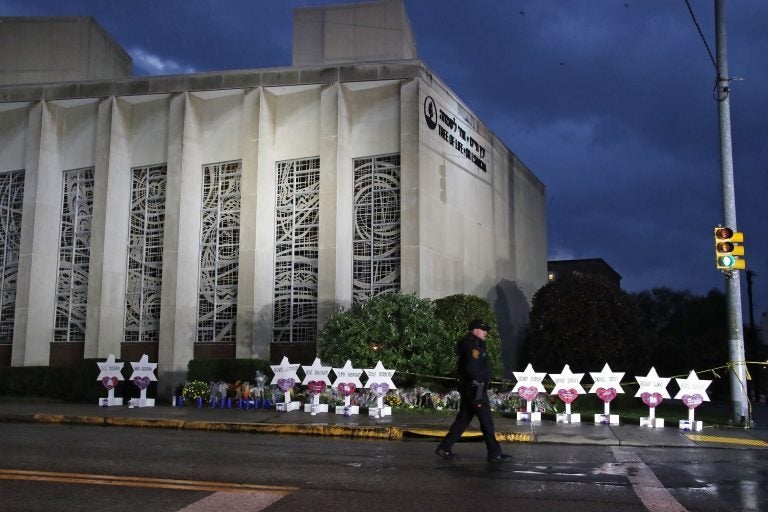 In this Oct. 28, 2018, file photo a Pittsburgh Police officer walks past the Tree of Life Synagogue and a memorial of flowers and stars in Pittsburgh in remembrance of those killed and injured when a shooter opened fire during services Saturday at the synagogue. (Gene J. Puskar/AP Photo, File)