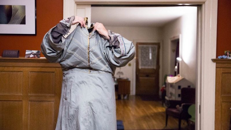 Walt Maguire pulls his floor-length Dumbledore robe over his head at his home in Germantown on the morning of Oct. 20, 2017. Maguire played the part of Dumbledore at the Chestnut Hill Harry Potter Festival for six years and would begin getting ready at 5 a.m. (Rachel Wisniewski for WHYY)