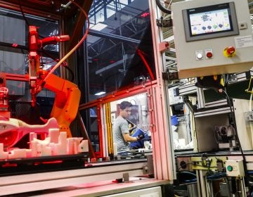 In this 2017 photo, an assembly line laborer works alongside a collaborative robot, left, on a chainsaw production line. (AP Photo/John Minchillo)