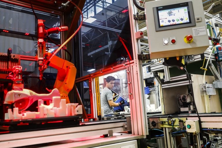 In this 2017 photo, an assembly line laborer works alongside a collaborative robot, left, on a chainsaw production line. (AP Photo/John Minchillo)