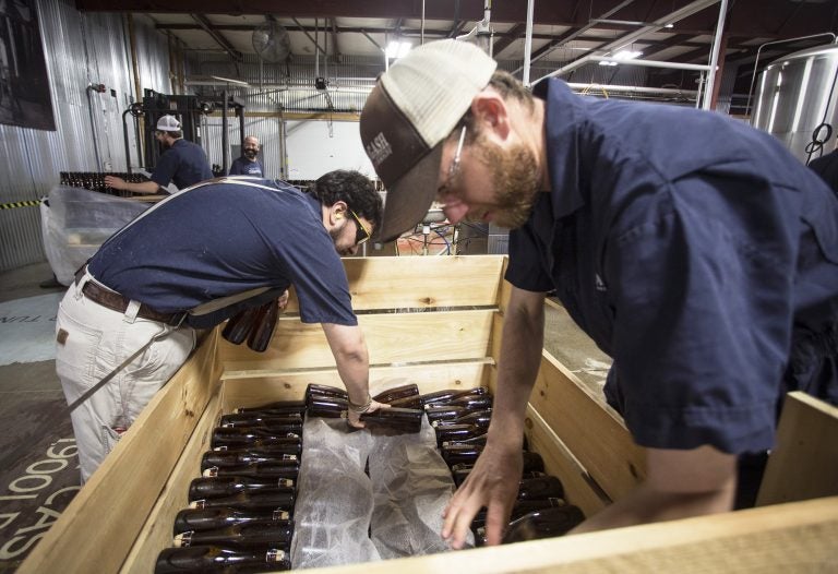 Allagash employees Salim Raal, left, and Brendan McKay stack bottles of Golden Brett, a limited release beer fermented with a house strain of Brettanomyces yeast. The Maine brewery recently installed solar panels as part of its sustainability initiatives. (Derek Davis/Portland Press Herald via Getty Images)