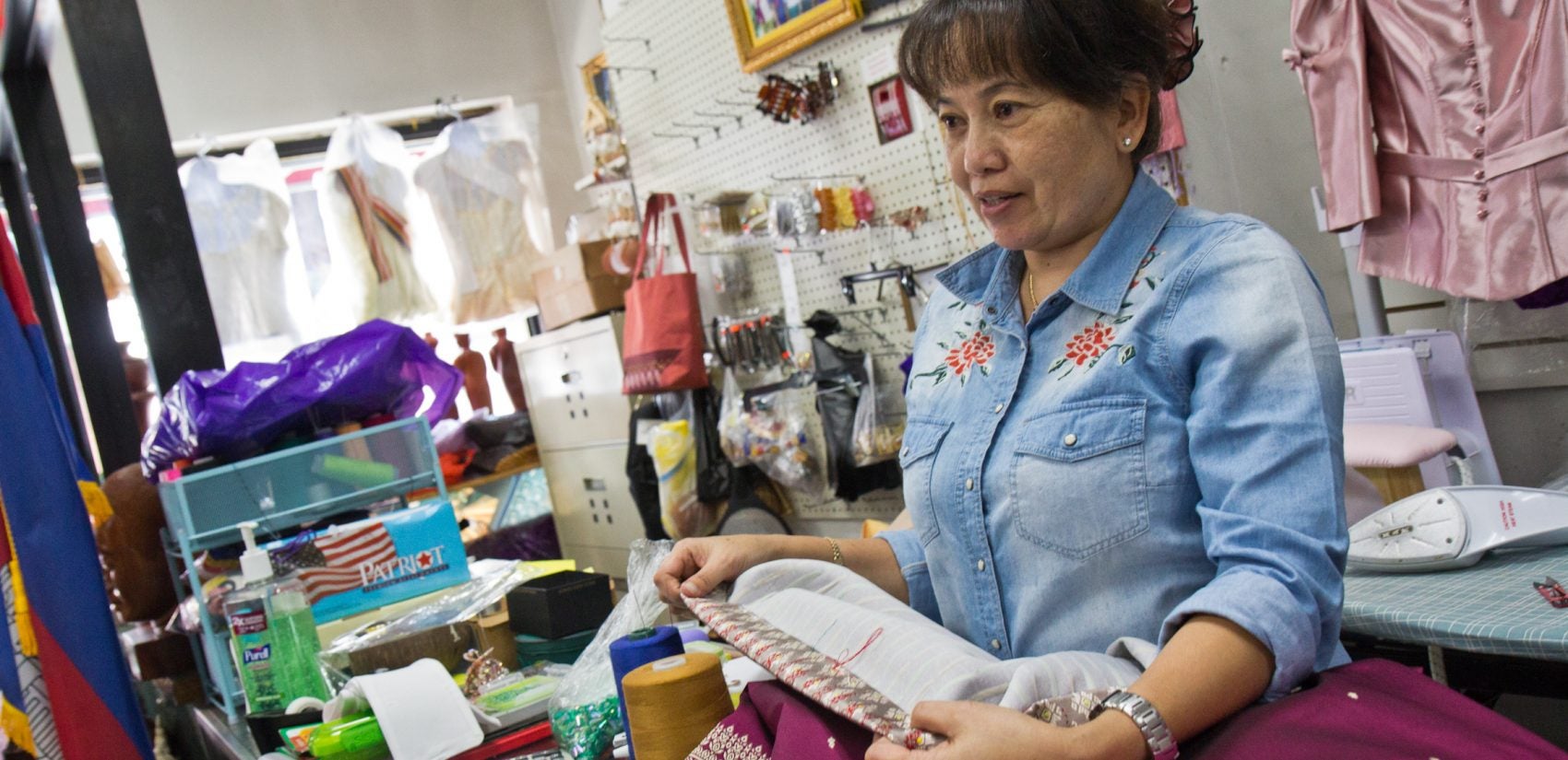 Phally Seng sews in her dress shop on South 7th Street. (Kimberly Paynter/WHYY)