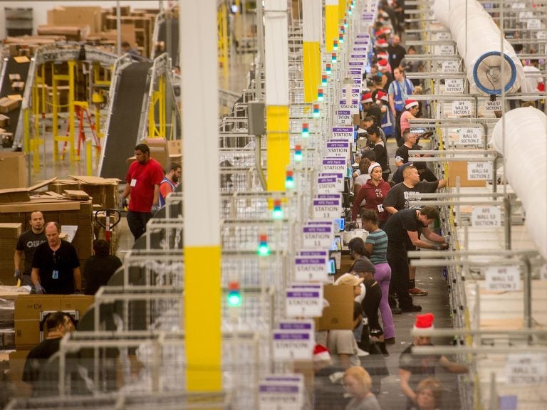 Amazon says it will pay all its U.S. workers at least $15. Here, workers prepare shipments at an Amazon Fulfillment Center in California during the early Christmas rush in 2014