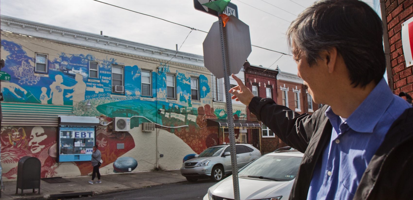 Andy Toy gestures to a mural that created controversy at 7th and Wolf because of it highlighted gambling addiction. (Kimberly Paynter/WHYY)