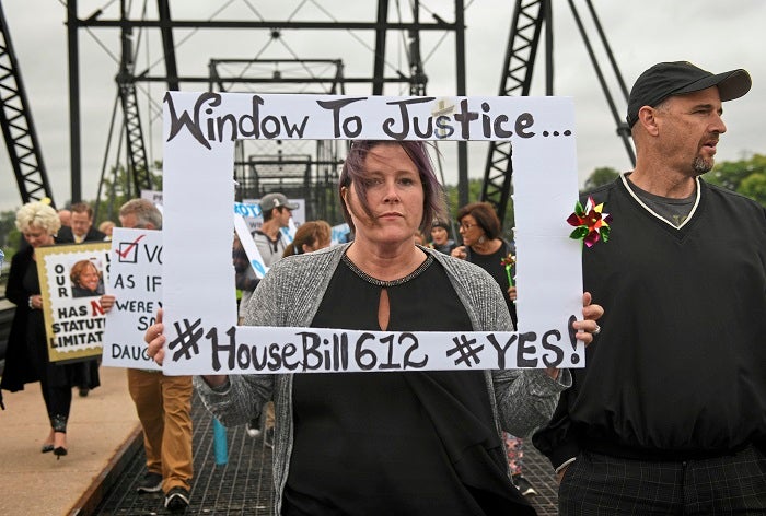 Kelly Williams carries a sign voicing support for legislation that would change the statute of limitations for child sex crimes, during a march in Harrisburg, Pa., Monday, Sept. 24, 2018. At right is her husband Brent. A proposal to give victims of child sexual abuse a two-year window to sue over allegations that would otherwise be too old to pursue was overwhelmingly approved by the state House on Monday, as supporters cheered from the gallery. (Steve Mellon/Pittsburgh Post-Gazette via AP)