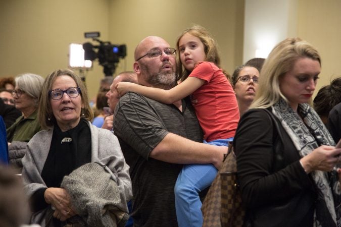 Jason Glass holds his daughter Lexi, 7, as he explains what the numbers on the screens mean in relation to the midterm election. Their family joined the hundreds of supporters who came out to support various Pennsylvania Democratic candidates at the official watch party for Mary Gay Scanlon in Swarthmore, Pa. on November 6, 2018. (Emily Cohen for WHYY)