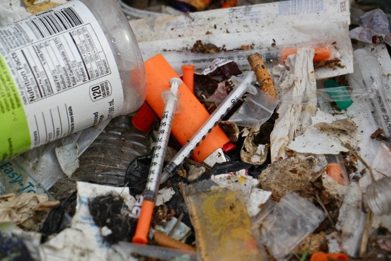 Syringes litter a block-long stretch of grass between Gurney Street and the Conrail tracks in Kensington. (Emma Lee/WHYY)