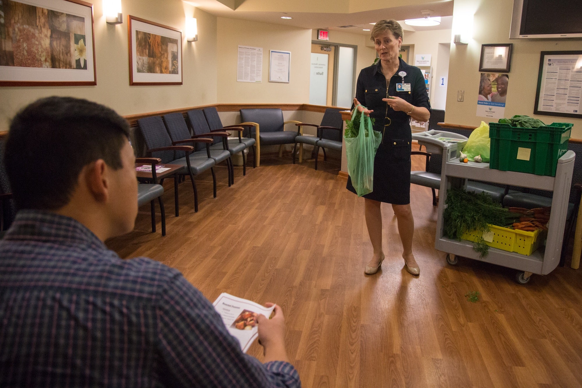 Maureen Krouse talks to Jason Paik about the produce from the hospital's wellness farm, available to him in the waiting room at Lankenau Hospital's integrated health practice. 