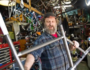 Stephen Bilenky holds a steel bike frame at Bilenky Cycle Works in Philadelphia. (Kimberly Paynter/WHYY)