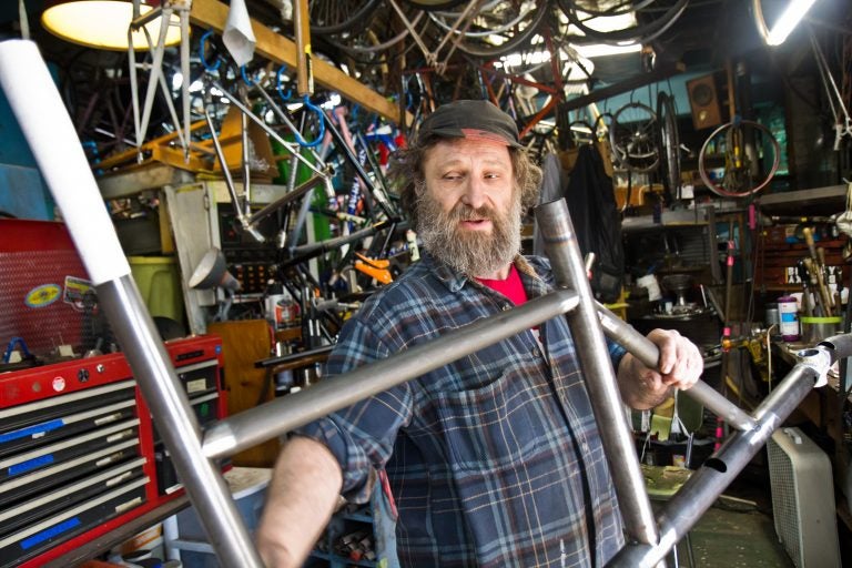 Stephen Bilenky holds a steel bike frame at Bilenky Cycle Works in Philadelphia. (Kimberly Paynter/WHYY)