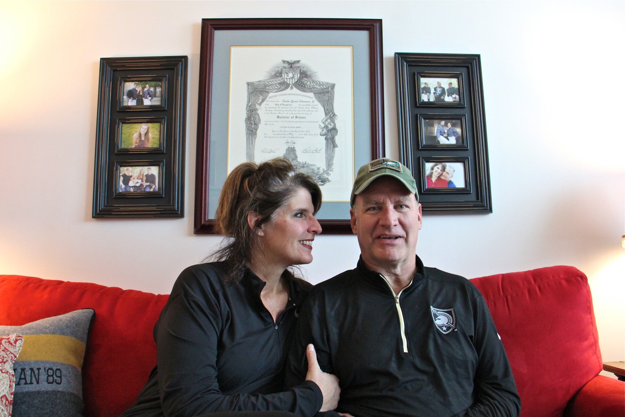 Chuck Schretzman and his wife, Stacy, pose in front of his framed diploma from West Point and photos of their three children. 