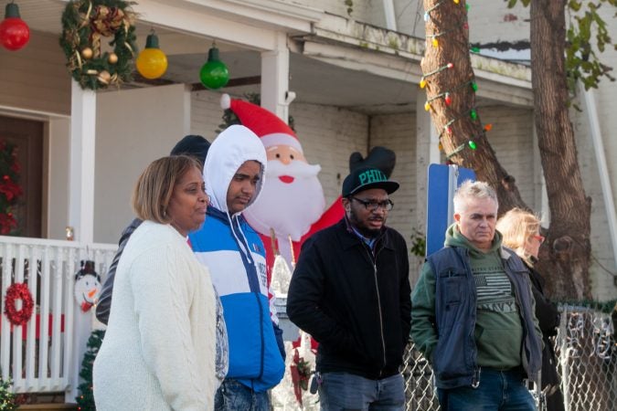 The Mella family, left, stand near their home during a gathering of Tacony residents and neighbors who came out on Saturday to show support for the family who received a threatening and racist letter earlier this month. (Brad Larrison for WHYY)